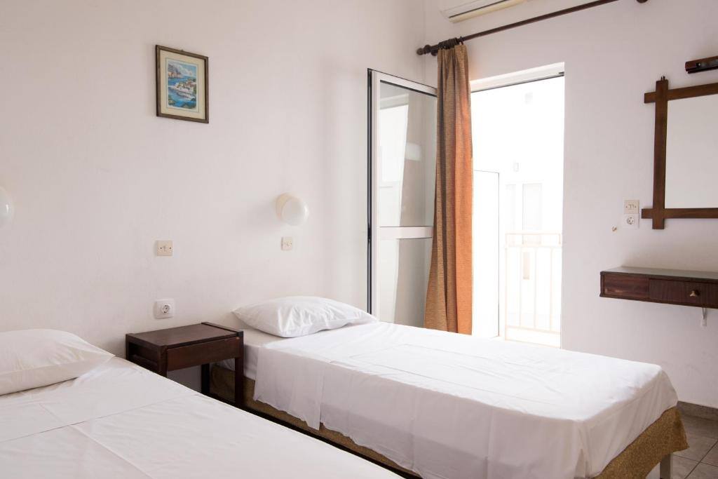 Twin beds with white linens beside a balcony door